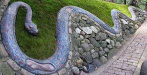 sculpture of a snake, built into a retaining wall; below his squiggly curves are stones