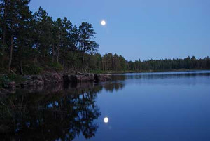 a remote lake; the rising moon is reflected in the still water