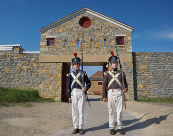 2 "soldiers" wearing historically accurate costumes, in front of the history fort