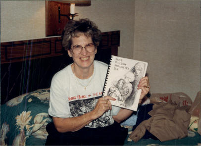 JoAnn Grant showing the SND zine "Love has not forgotten you", written by Sandy P. Shelton, illustrated by Sandy C. Shelton