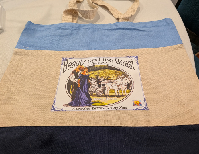 a canvas bag, light blue on the top, dark blue on the bottom, natural canvas color in the middle; with con logo on one side